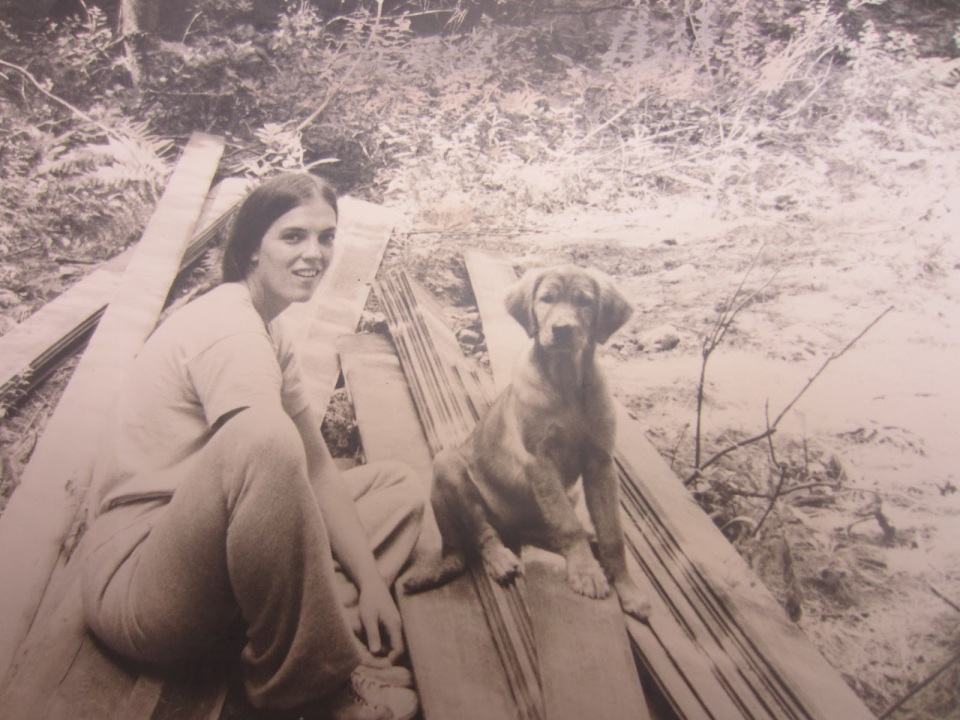 Wrinx the golden retriever and Marcy, 1976, sitting on a pile of wood 